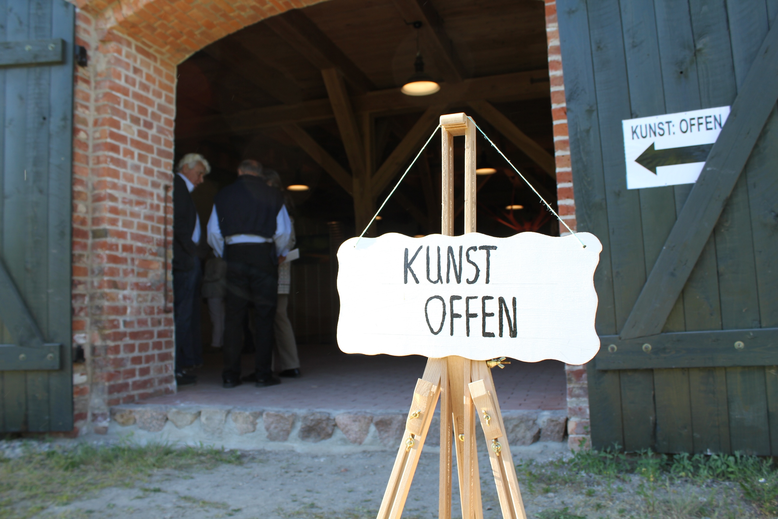 Ein Schild, auf dem "KUNST OFFEN" steht, vor einer Scheune.